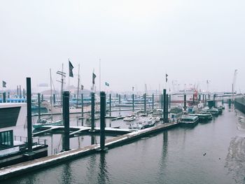 Boats moored at harbor against sky during foggy weather