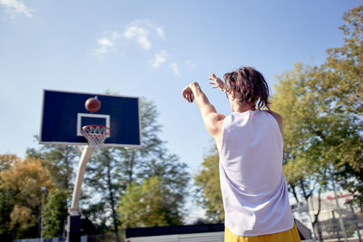 Man holding basketball hoop against sky