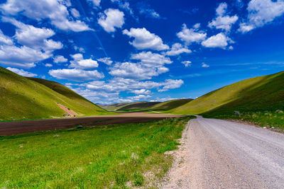 Road amidst field against sky