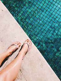 Low section of woman standing by swimming pool