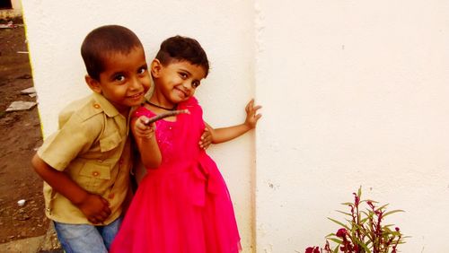 Siblings standing against wall