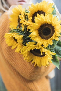 Midsection of woman holding sunflowers