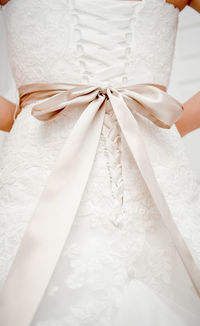 Midsection of bride with tied bow on wedding dress