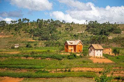 House on field by trees against sky