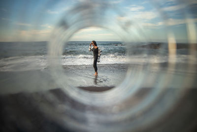 Woman standing in sea against sky