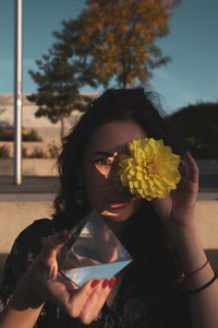 Portrait of young woman holding yellow flower