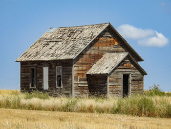 An old abandoned farm house on a hill in a grassy prairie