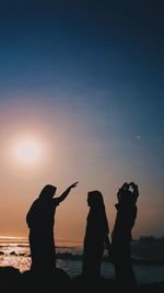 Silhouette people photographing against sky during sunset