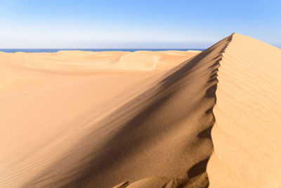 Sand dunes in desert against clear sky