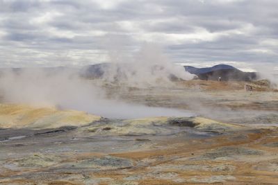 Smoke emitting from volcanic landscape against sky