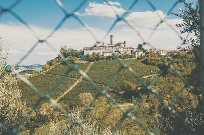 Buildings on mountains seen through chainlink fence