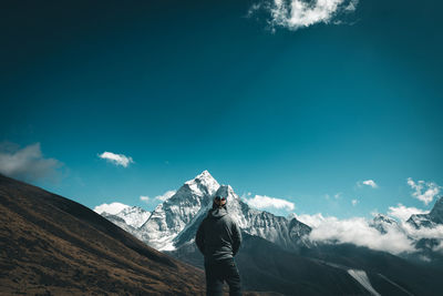 Man standing on snowcapped mountain against sky