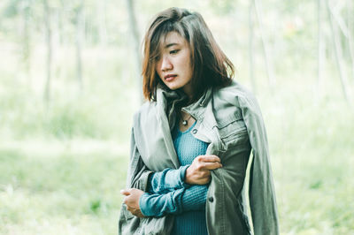 Beautiful young woman standing against trees