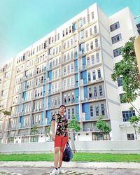 Portrait of young woman standing against building