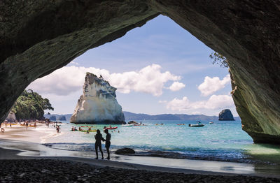 Couple in cave at beach against sky