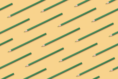 Pattern composition of green pencils on a yellow background. top view. flat lay. back to school