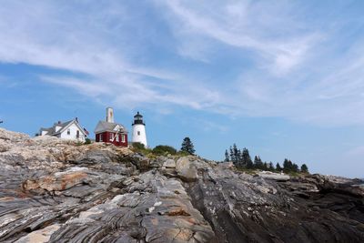 Low angle view of lighthouse and houses on mountain against sky