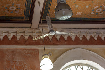 Low angle view of electric lamp hanging on ceiling of building