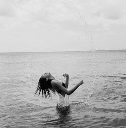 Woman standing in sea against sky