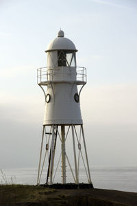 Lighthouse by sea against sky