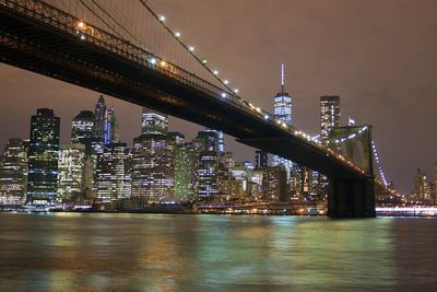 Illuminated bridge over river against sky at night