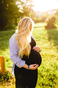 Beautiful pregnant woman standing on field