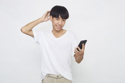 Young man using smart phone against white background