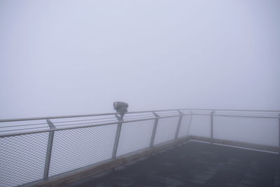 Metal railing on bridge against sky