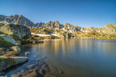 Scenic view of lake and mountains against clear blue sky