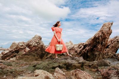 Woman standing on rock against sky