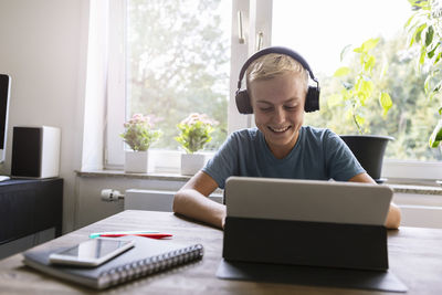 Smiling teenager using laptop at home