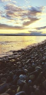 Surface level of beach against sky during sunset