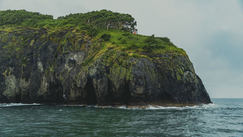 Rock formation in sea against sky