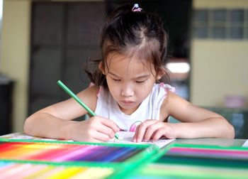 Portrait of cute girl with multi colored face on table