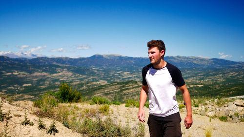 Young man standing on mountain against sky