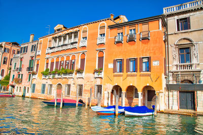 Boats moored in canal by buildings in city