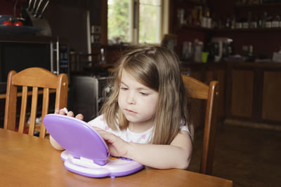 Young girl sitting and playing on preschool tablet