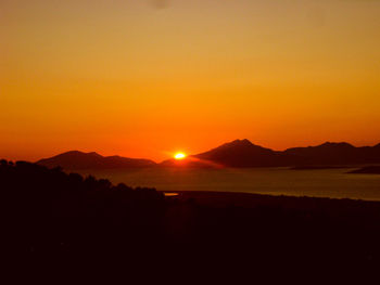 Scenic view of silhouette mountains against romantic sky at sunset