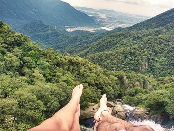 Low section of people on mountain against sky