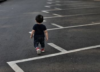 Rear view of baby boy walking on road
