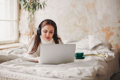 Young woman using mobile phone on bed at home