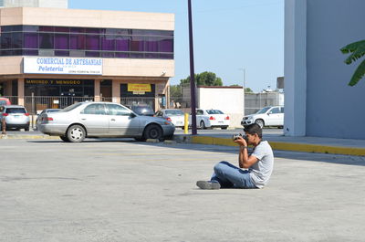 Man sitting on street in city