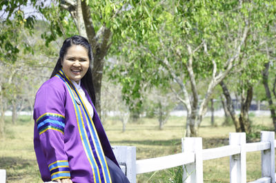 Portrait of young woman standing against trees