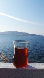 Close-up of drink in sea against sky