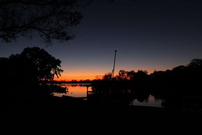 Silhouette trees by lake against sky during sunset