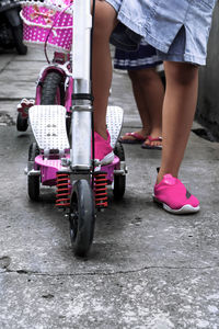 Low section of girl riding push scooter