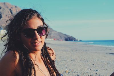 Close-up portrait of young woman in sunglasses at beach
