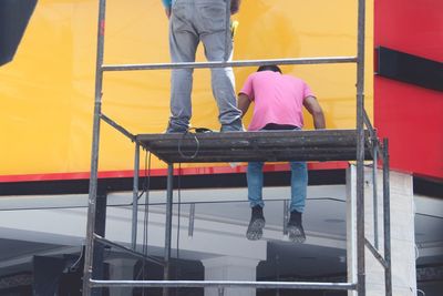 Rear view low section of men with yellow umbrella