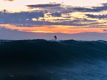 Silhouette person on mountain against sky during sunset
