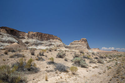 Rock formations on landscape against clear blue sky